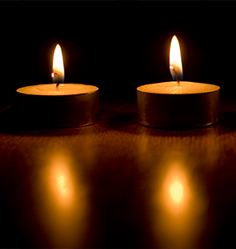 Drei brennende Kerzen auf dunklem Hintergrund.