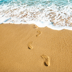 Spuren im Sand entlang der Küste, von der Brandung umspült.