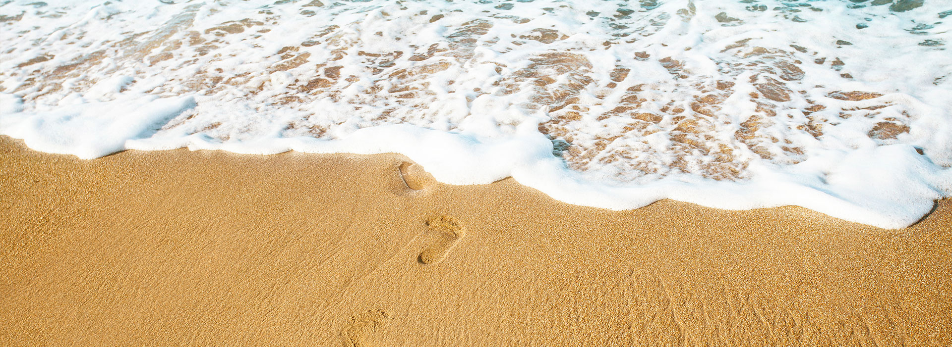 Spuren im Sand entlang der Küste, von der Brandung umspült.
